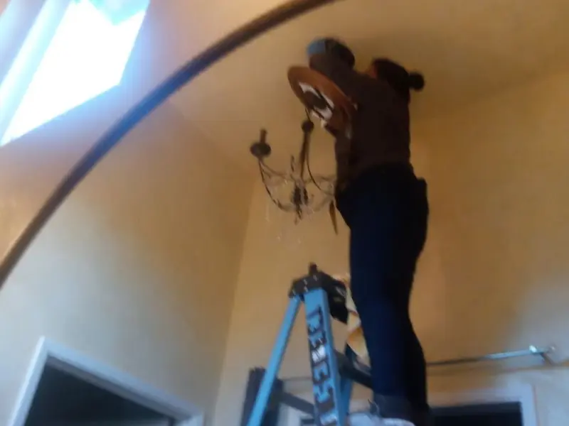 Electrician installing a chandelier in a South Harrison residence